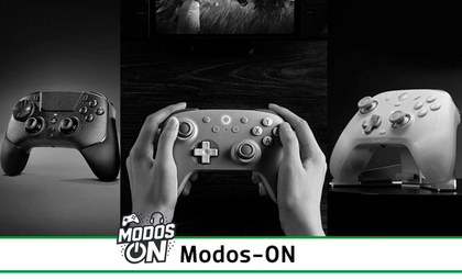 Tres mandos de diferentes consolas, el que está en el centro está sujetado por una persona con ambas manos.